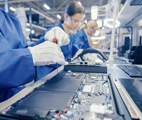 People stand on an assembly line working on electronic parts