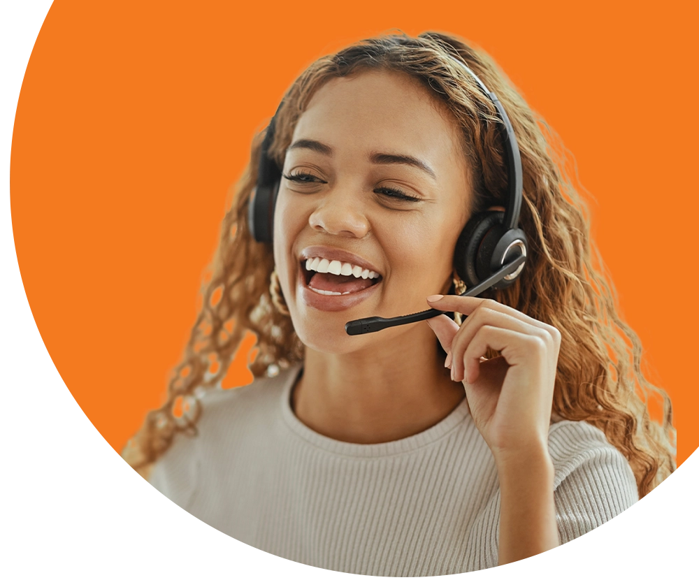 A woman wearing a headset smiles while speaking to a customer